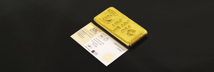 Gold cast bar alongside of an ABC Bullion business card